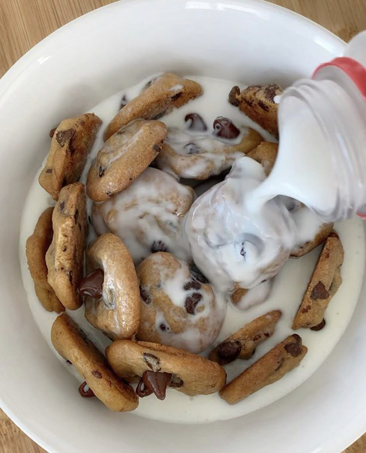 a white bowl filled with cookies and cream on top of a wooden table next to a bottle