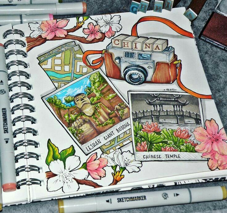 an open sketchbook with pictures and flowers on the pages, along with pens and markers