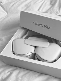 an airpods box on a bed with the lid open and four earbuds in it