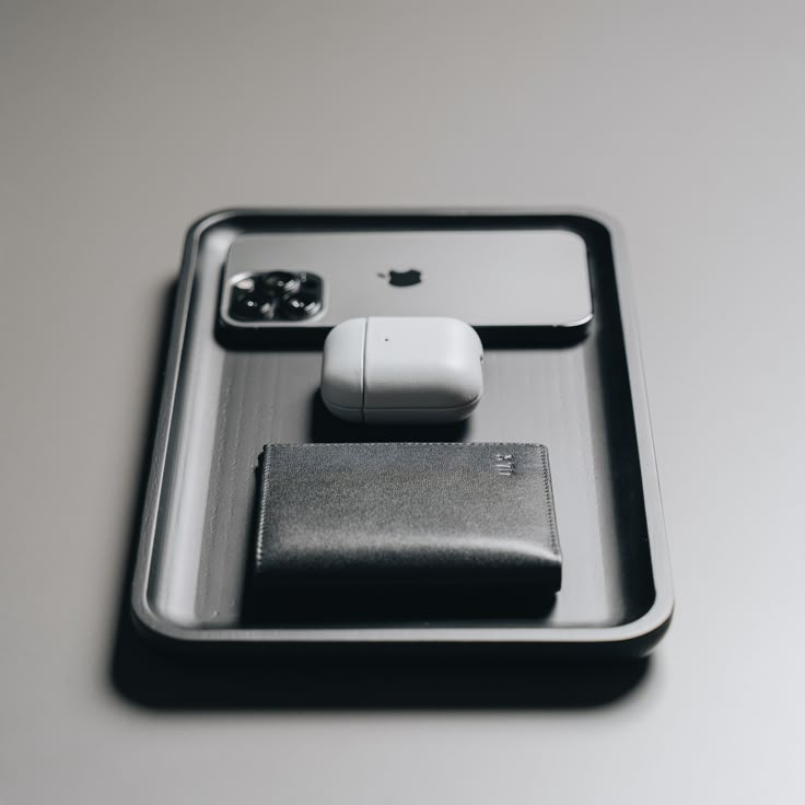 an apple product is sitting on a tray with other items in the tray, as well as a leather wallet