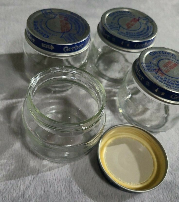 four jars with different types of cream in them on a white tableclothed surface