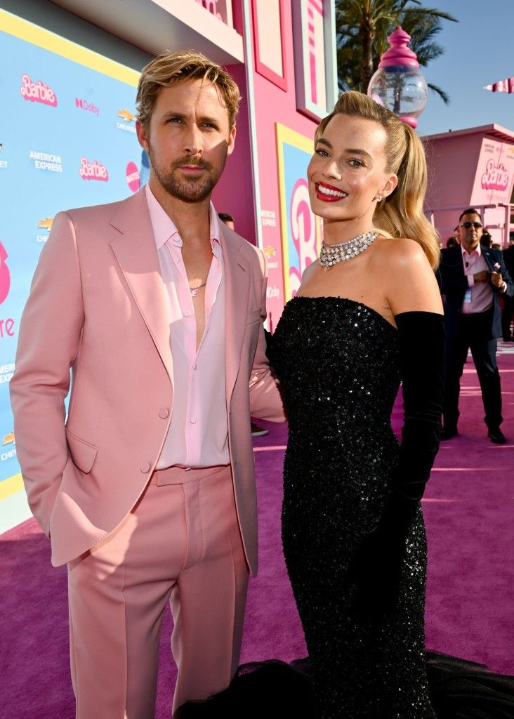 a man in a pink suit and woman in a black dress on the red carpet