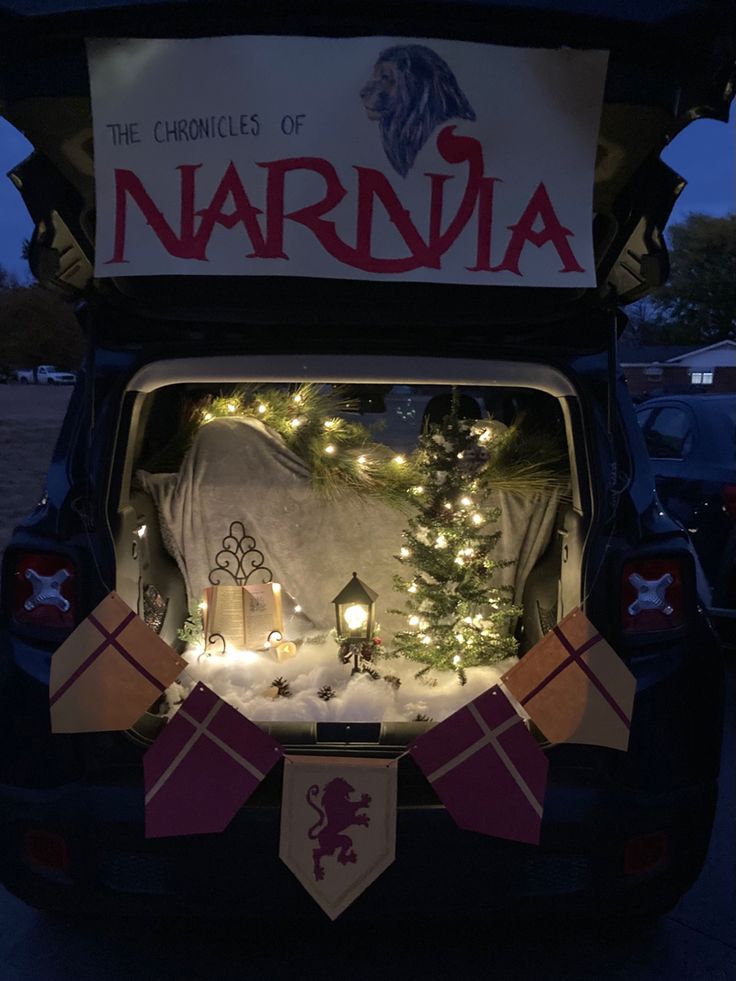 the back of a car with christmas lights and decorations on it's trunk, in front of a sign that says narnja