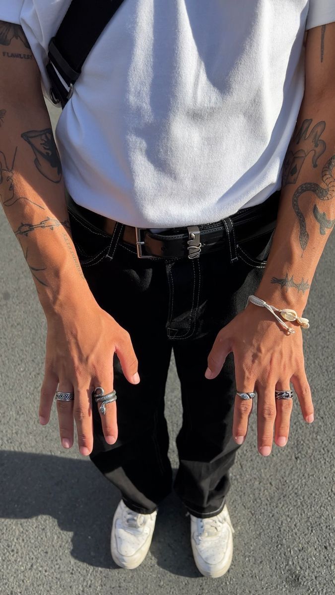 a person with tattoos on their arms and two hands in the air, wearing white sneakers