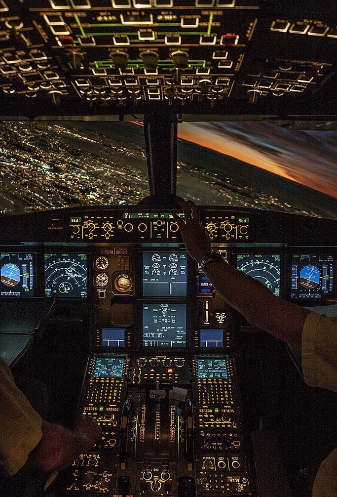 two pilots are in the cockpit of an airplane at night, looking down on the ground