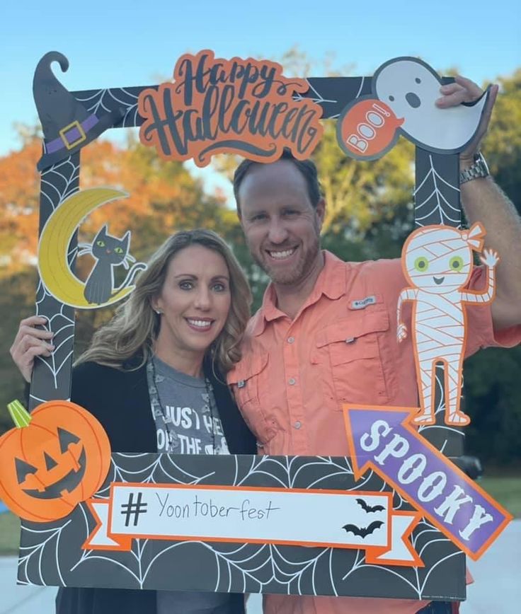 a man and woman holding up a halloween photo frame