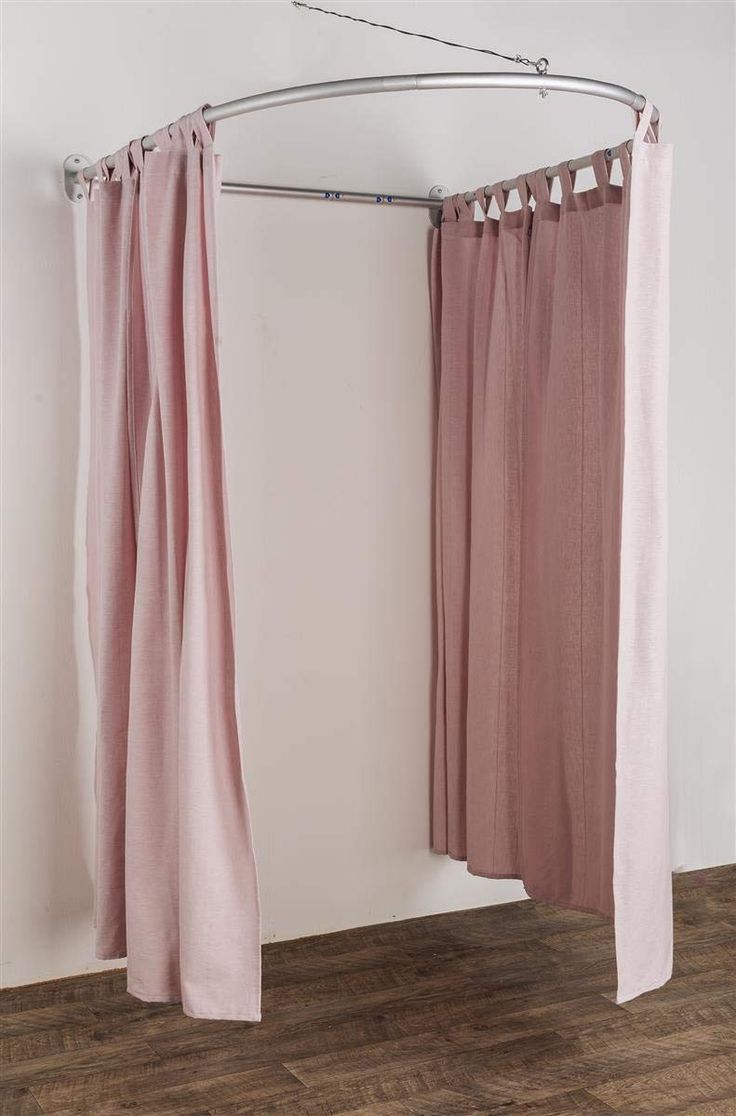 two pink curtains hanging on a metal rod in front of a white wall and wooden floor