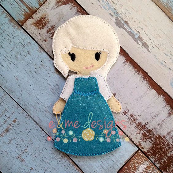 a small doll with a blue dress and white hair is sitting on a wooden surface