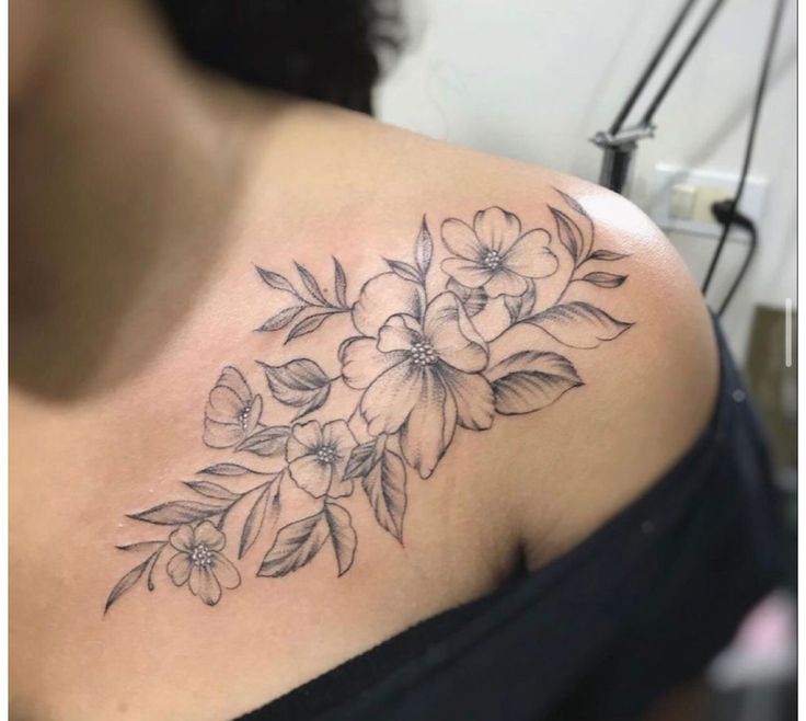 a woman's shoulder with flowers and leaves tattooed on her left side breast area