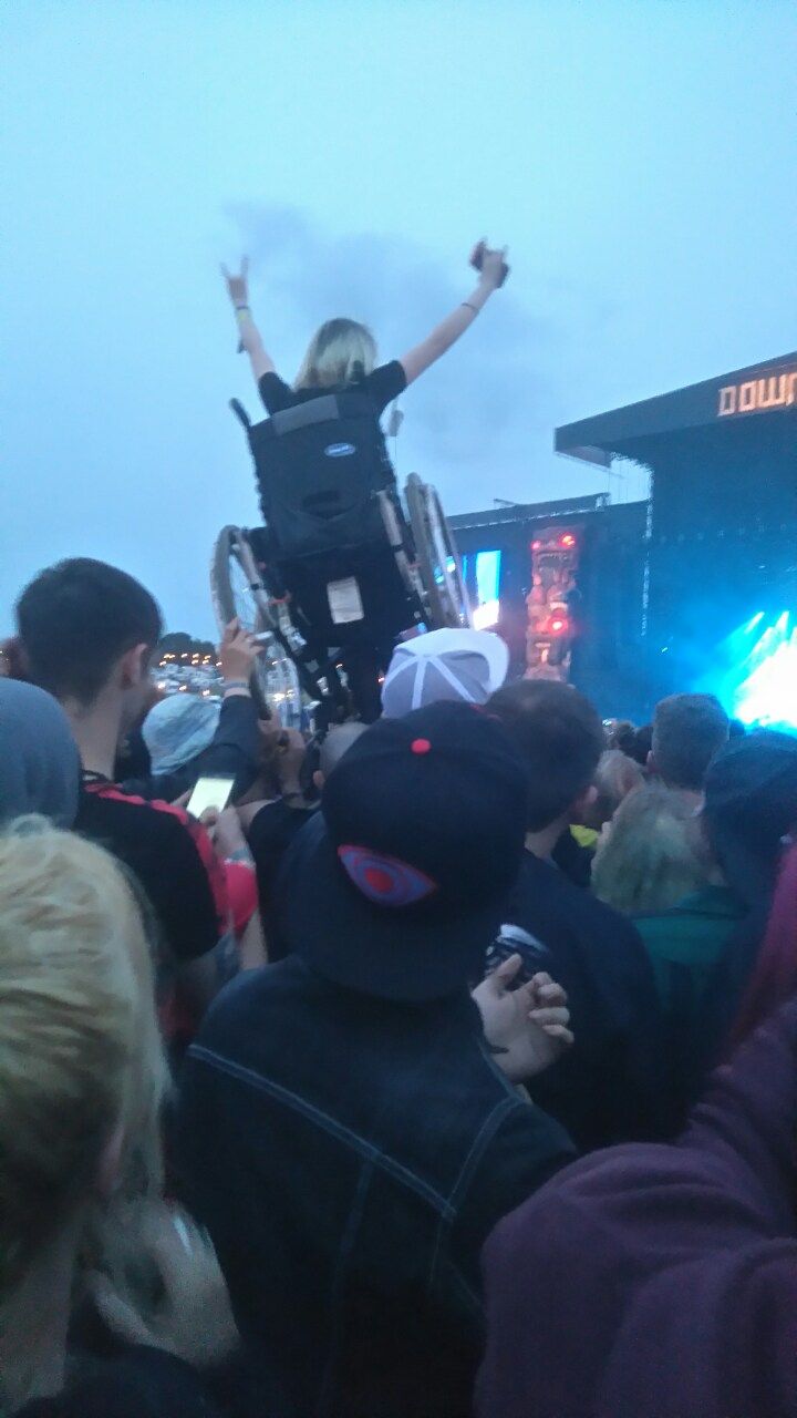 a woman in a wheel chair on top of a crowd at an outdoor music festival