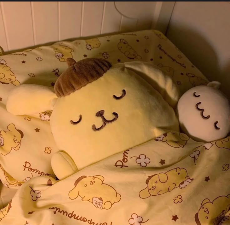 a yellow teddy bear laying on top of a bed