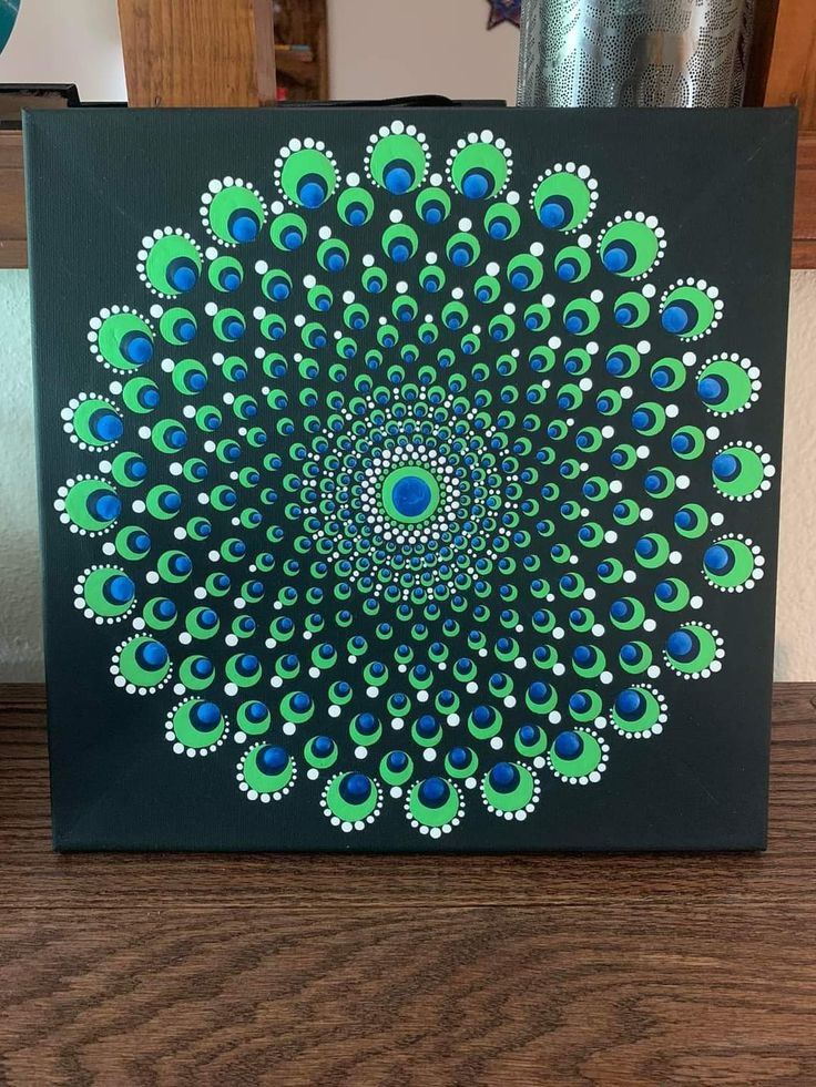 a painting on a wooden table with blue and green colors in the center is a peacock's tail