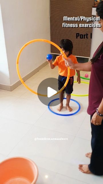 a woman is playing with a child on the floor in front of some hoops