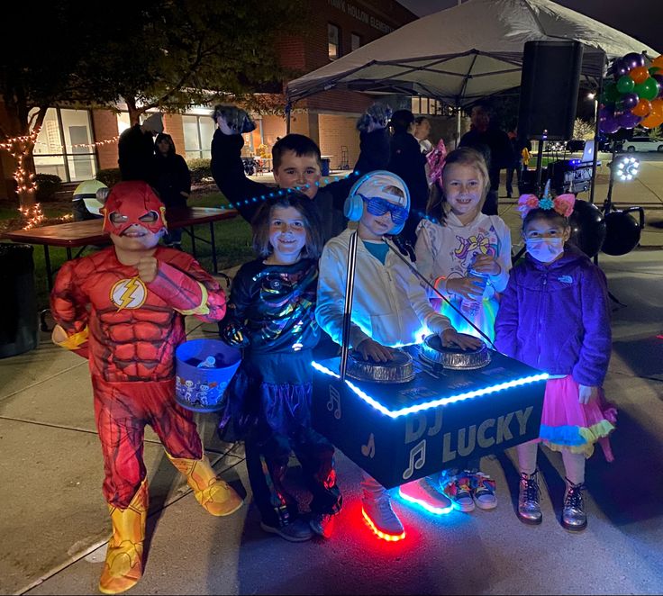 some kids are dressed up as superheros and dj's at an outdoor event