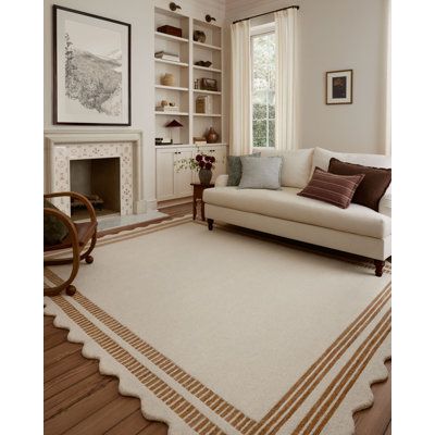 a living room filled with furniture and a white rug on top of a hard wood floor