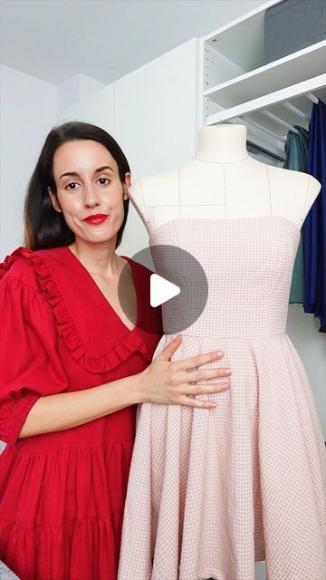 a woman standing in front of a dress on a mannequin with her arms crossed