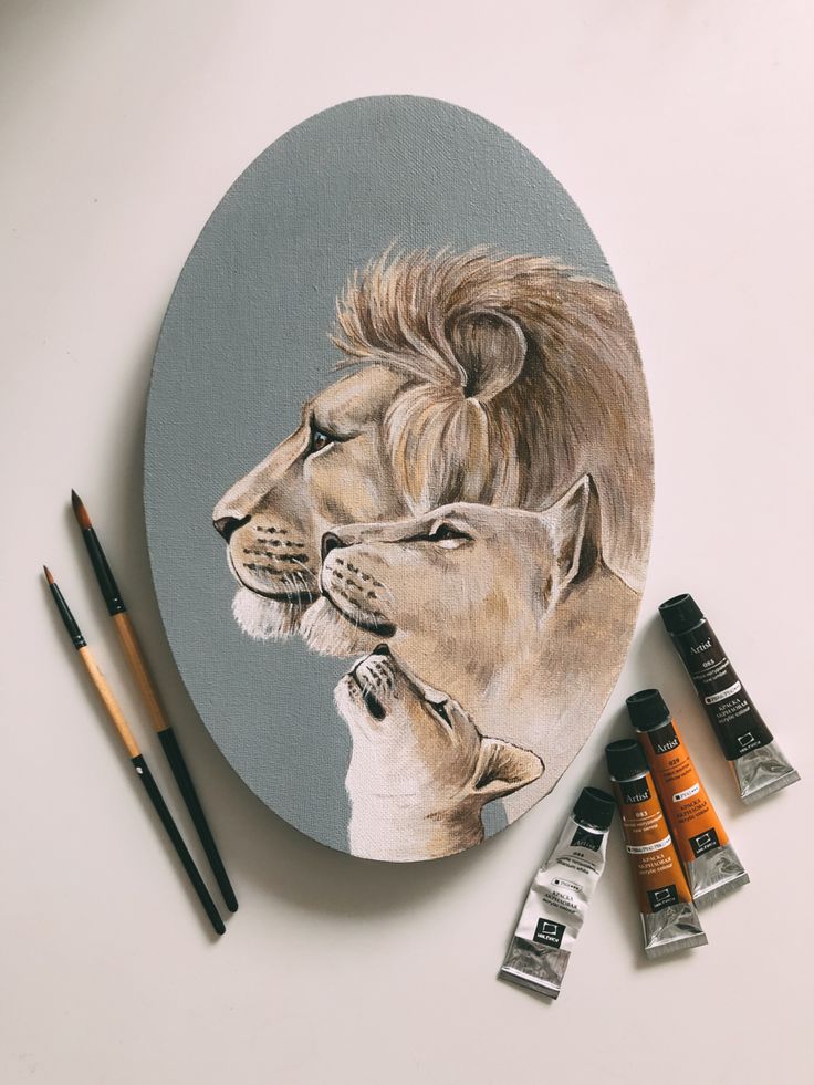 a drawing of two lions on a plate next to some paint tubes and markers,