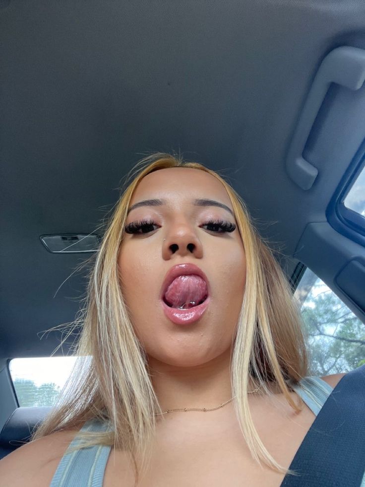 a woman sticking her tongue out while sitting in the back seat of a car,