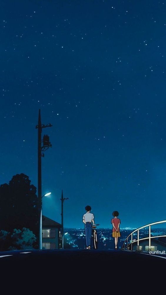 two people standing on a bridge looking at the night sky