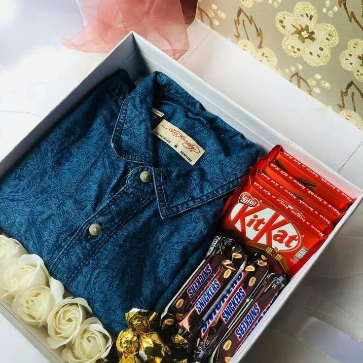 an open box with candy, chocolates and denim jacket in it on a table