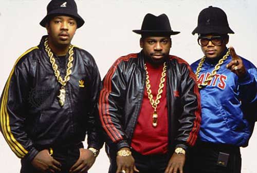 three men standing next to each other wearing black hats and jackets with gold chains on them