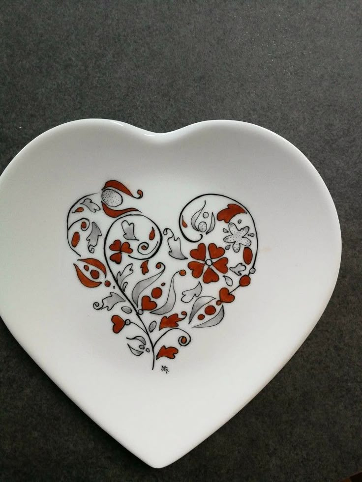 a heart shaped plate with red and white designs on it