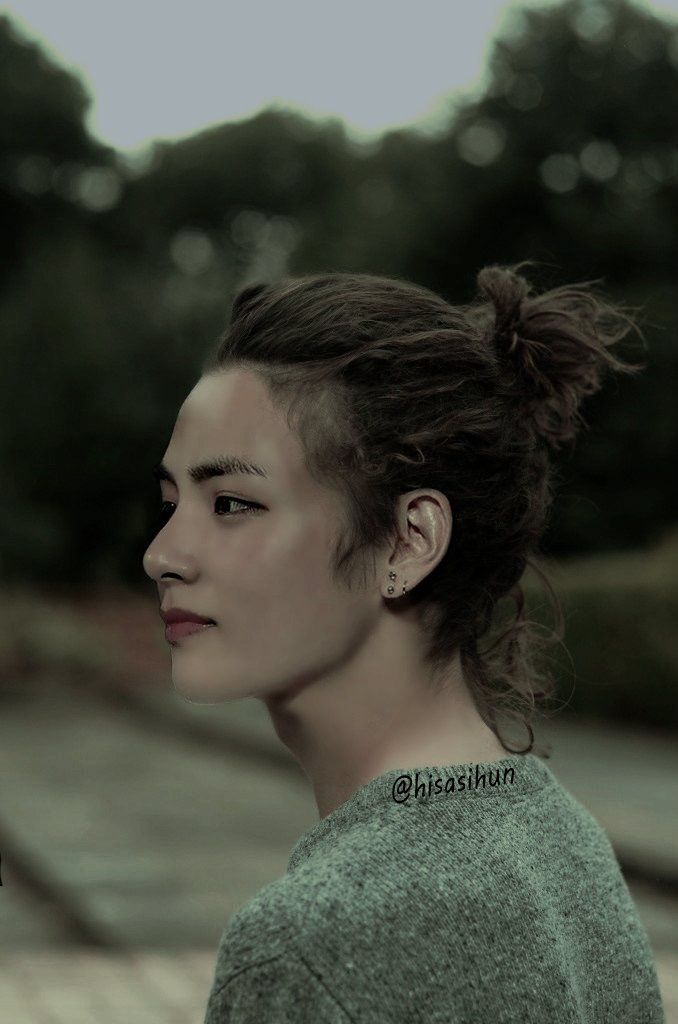 a woman with her hair in a bun and piercings looking off into the distance