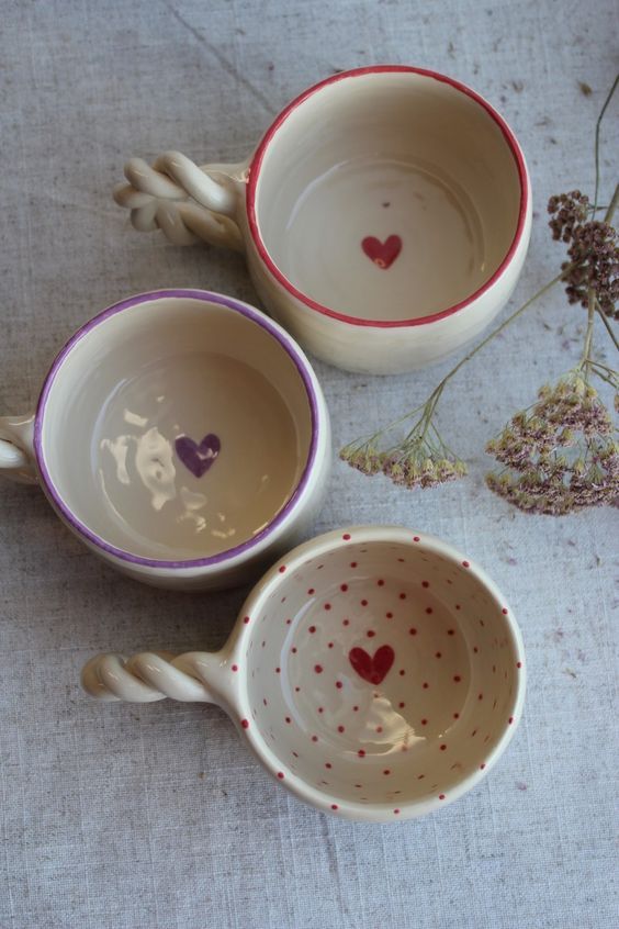 three small cups with hearts painted on them