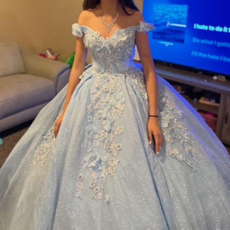 a woman in a blue ball gown standing next to a tv