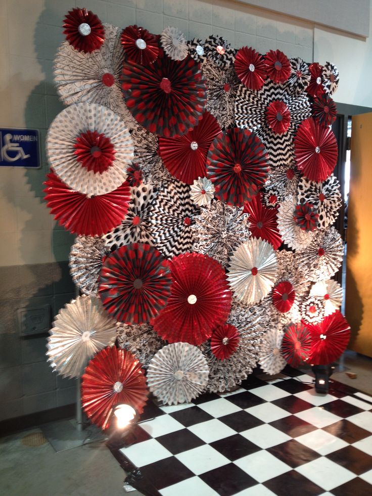 red and white paper fans are hanging on the wall next to a checkered floor