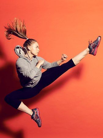 a woman is jumping in the air with her legs spread out and hair flying through the air