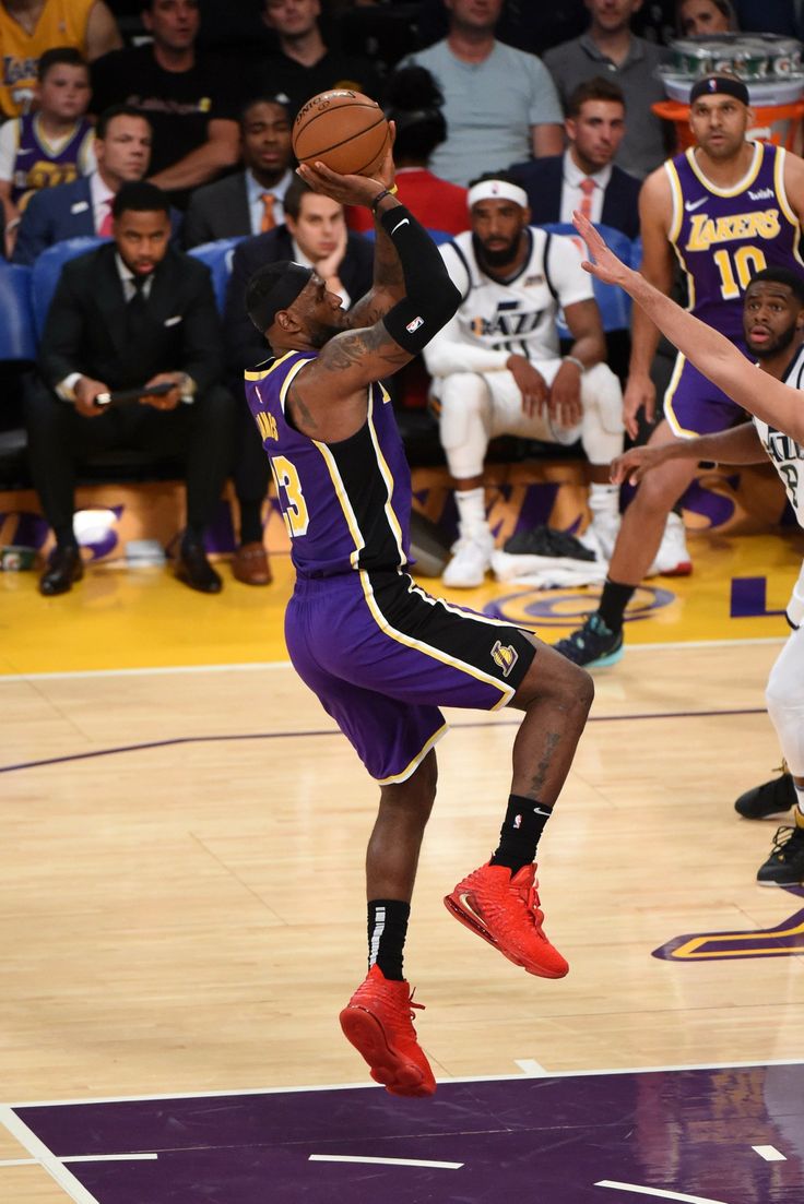 a basketball player jumping up to dunk the ball in front of other players and fans