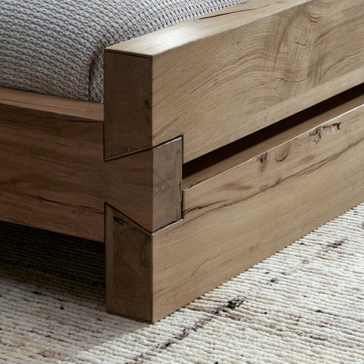 a wooden bed frame with two drawers on each side and a white rug in the background