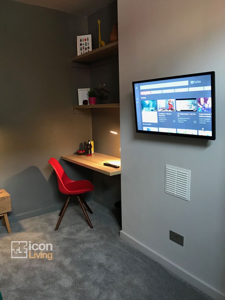 a flat screen tv mounted to the side of a wall next to a red chair