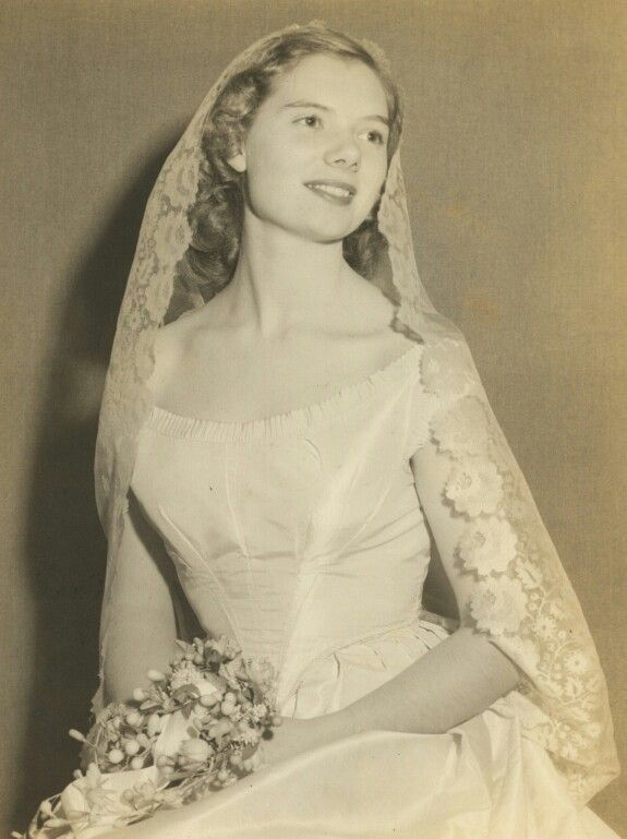 an old black and white photo of a woman in a wedding dress holding a bouquet