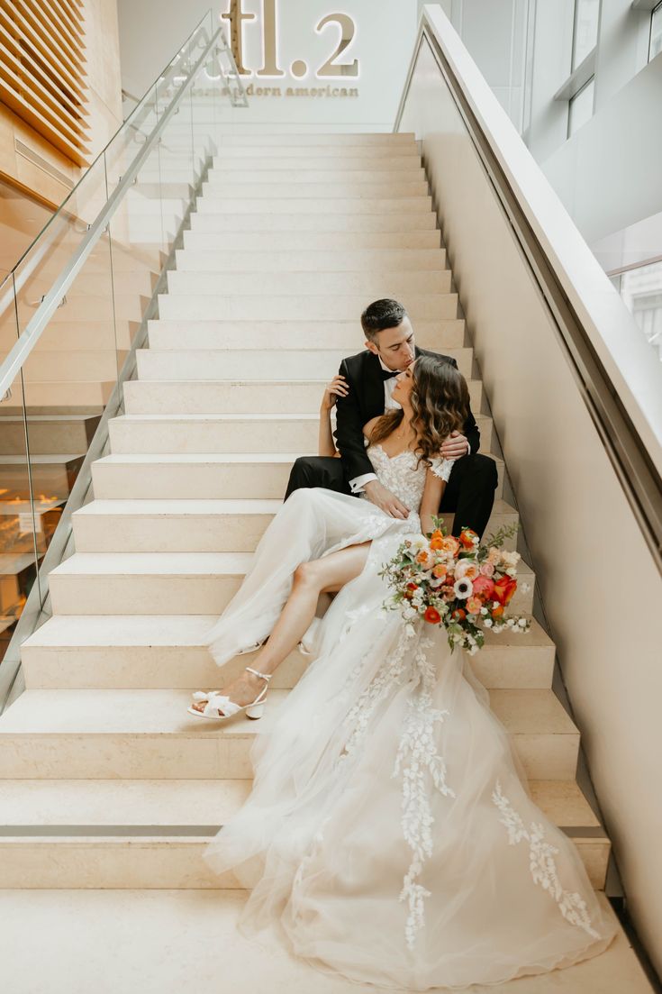 a bride and groom are sitting on the stairs