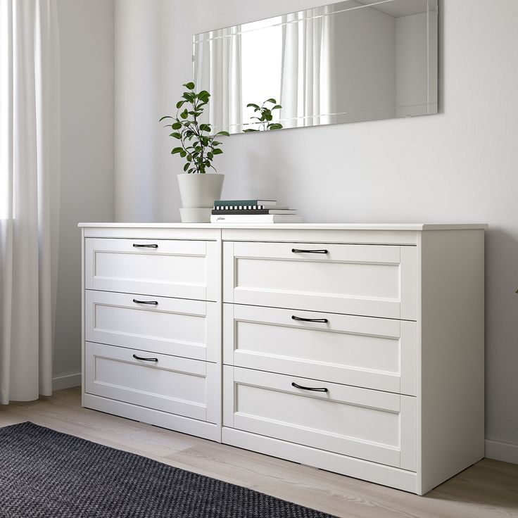 a white dresser with two drawers and a potted plant sitting on top of it