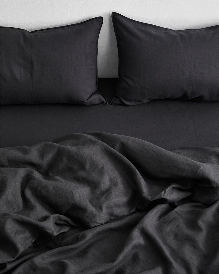 a bed with black sheets and pillows on it