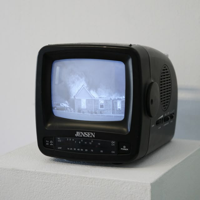 an old television sitting on top of a white block