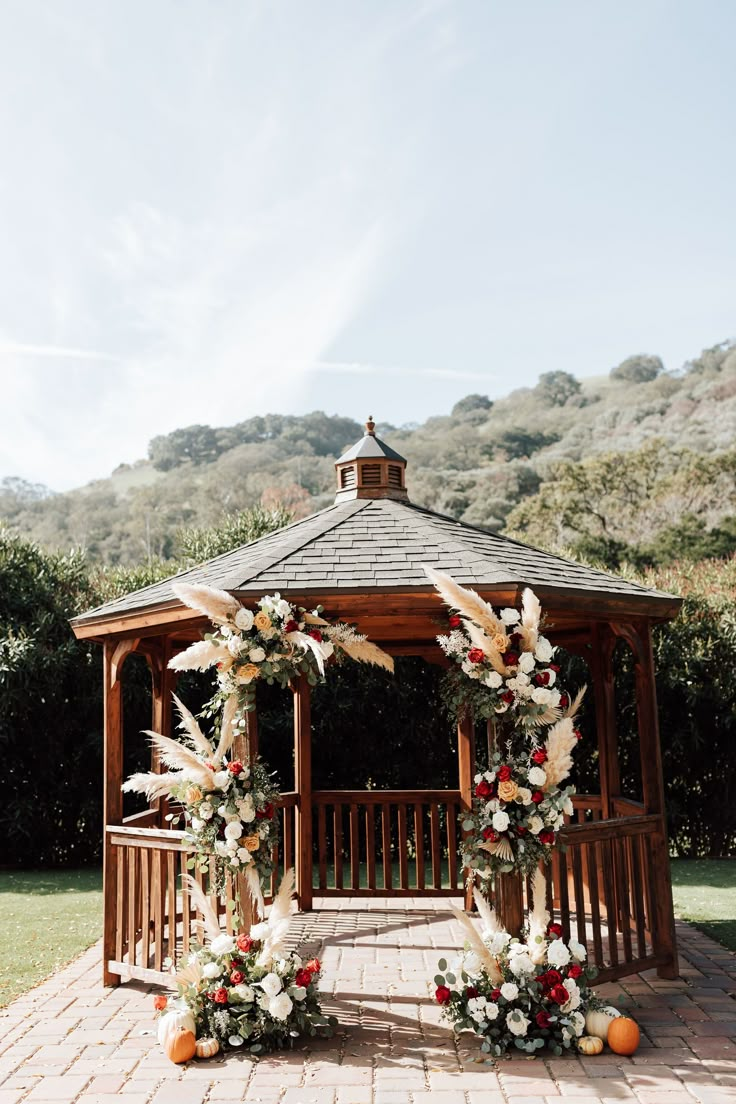 an outdoor gazebo decorated with flowers and feathers