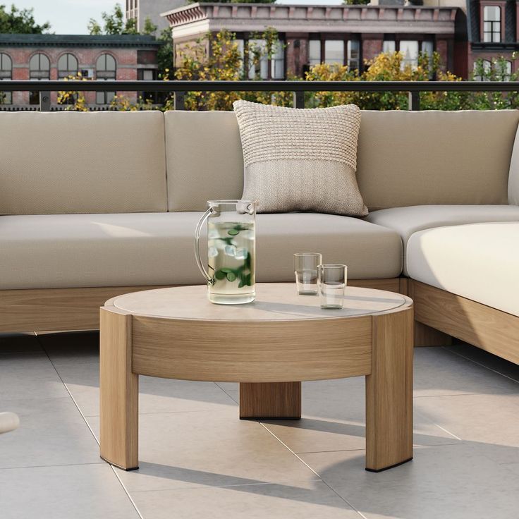 a couch and coffee table on a patio with buildings in the backgroung