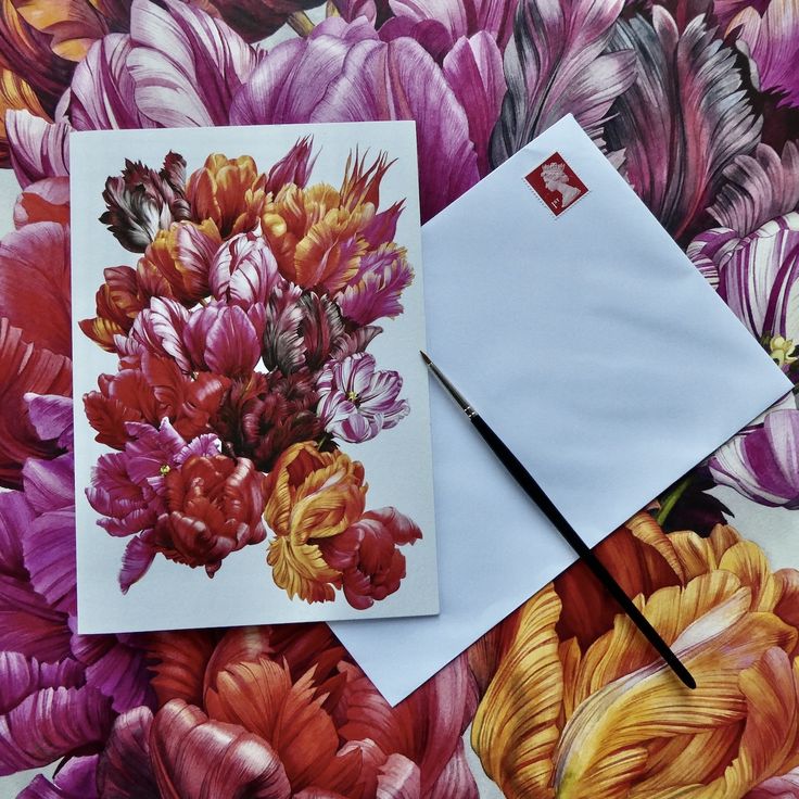 two envelopes with flowers on them and one has a pen in it next to the envelope