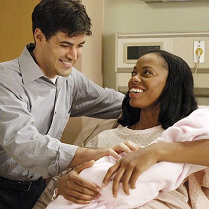 a man holding the hand of a woman who is laying in a hospital bed while she smiles