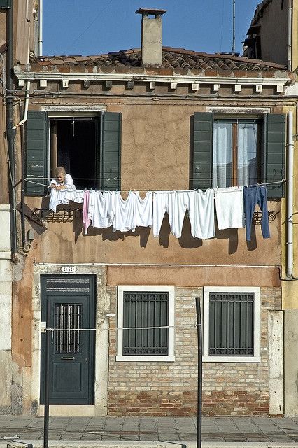 clothes hanging out to dry in front of an old building with windows and shutters