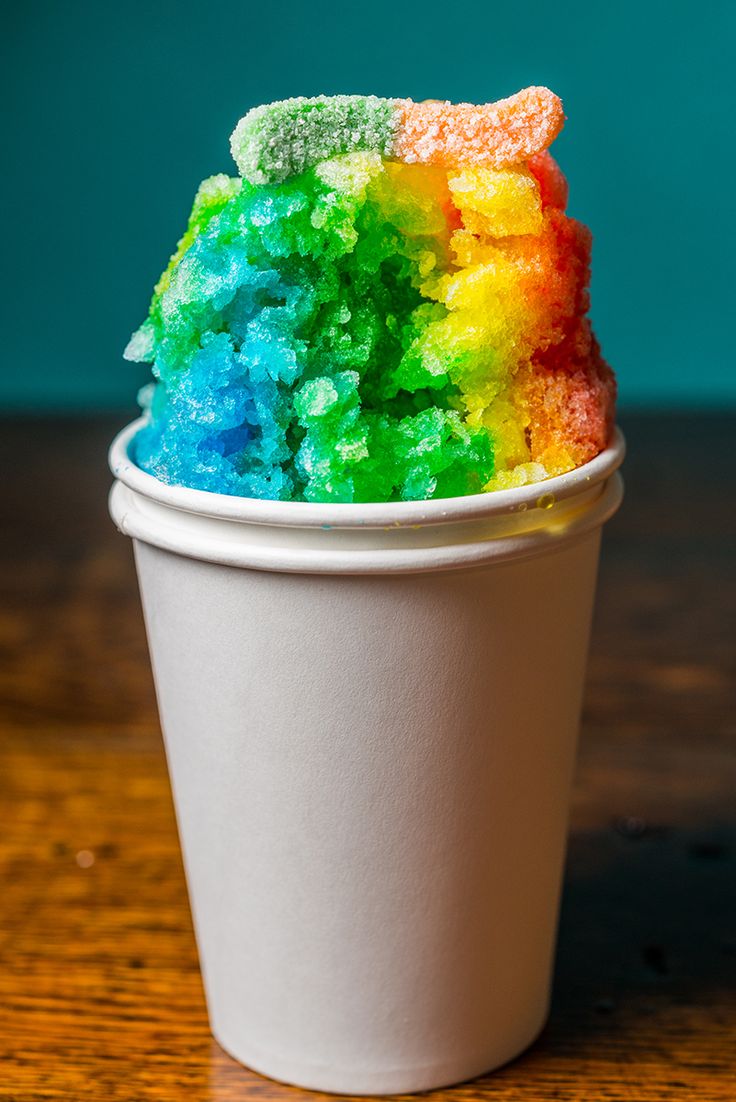 a cup filled with rainbow colored powder on top of a wooden table