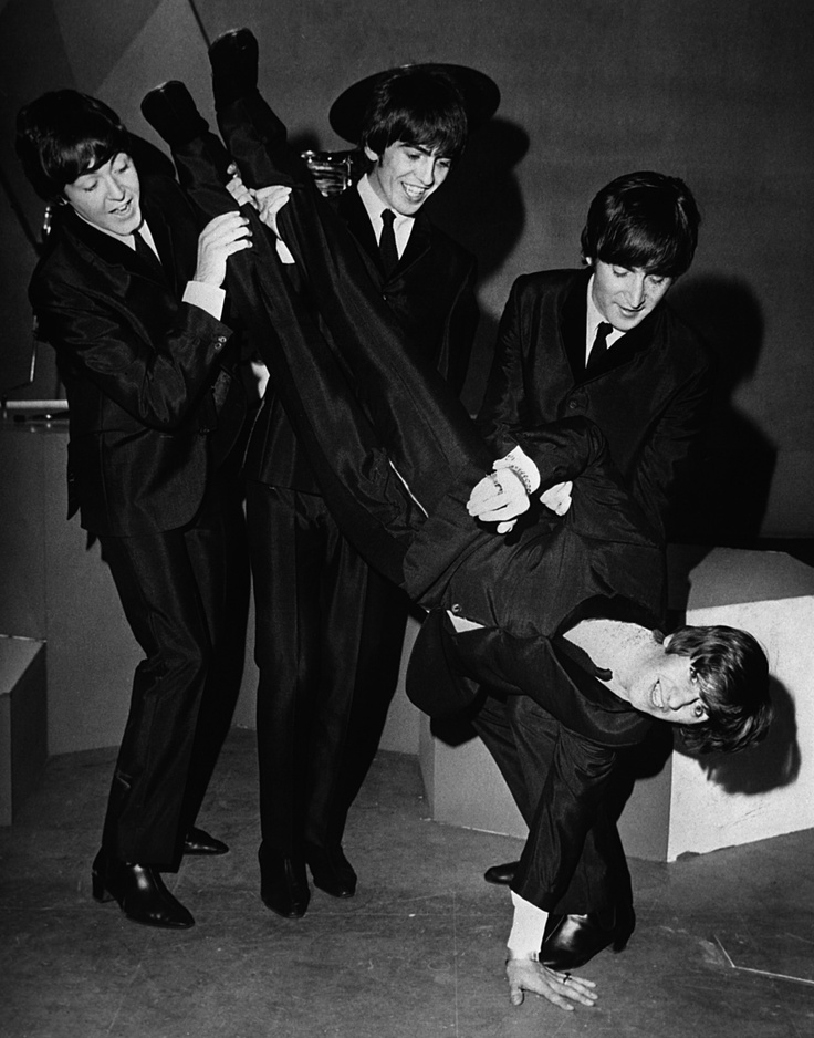 three men in suits and ties are holding onto one another's leg as they pose for the camera