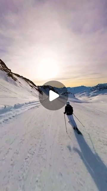 a person riding skis down a snow covered slope with the sun in the background