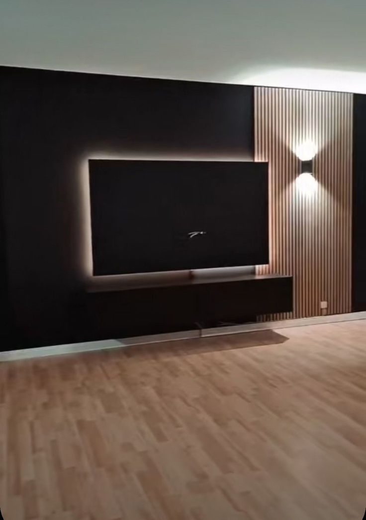 a living room with hard wood floors and black walls, along with a flat screen tv mounted on the wall