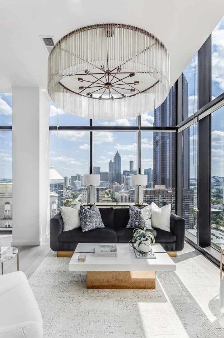 a living room filled with furniture next to tall windows and a chandelier hanging from the ceiling