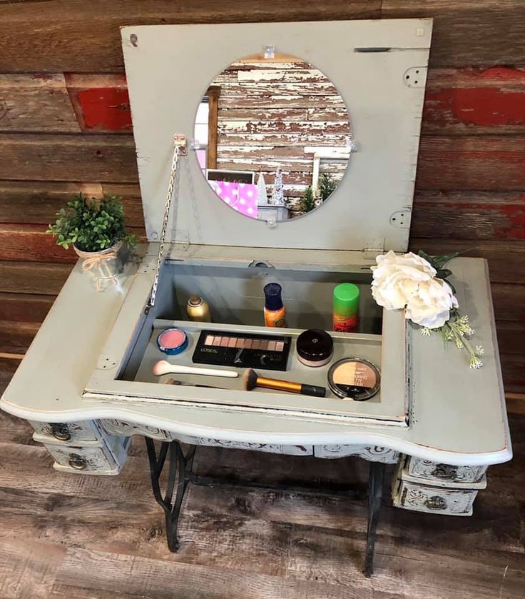 an old desk with a mirror on it and various makeup items in the drawer underneath